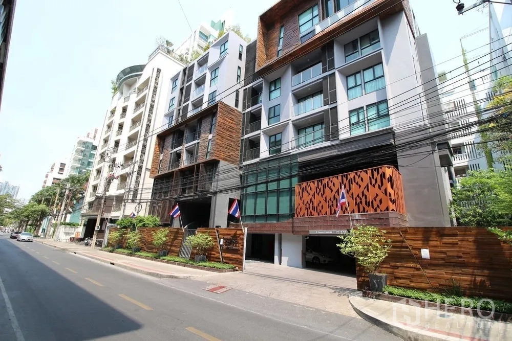 公寓 出租或出售在Watthana, Bangkok - 现代低层公寓外立面，木质与玻璃元素位于安静街道上。