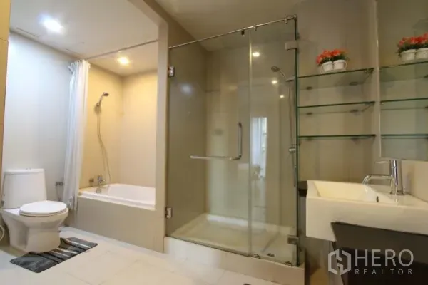 Condominium for rent in Watthana, Bangkok - Contemporary bathroom featuring a glass shower enclosure, bathtub, toilet and floating sink.