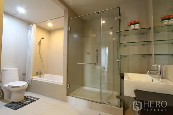 Condominium for rent in Watthana, Bangkok - Contemporary bathroom featuring a glass shower enclosure, bathtub, toilet and floating sink.