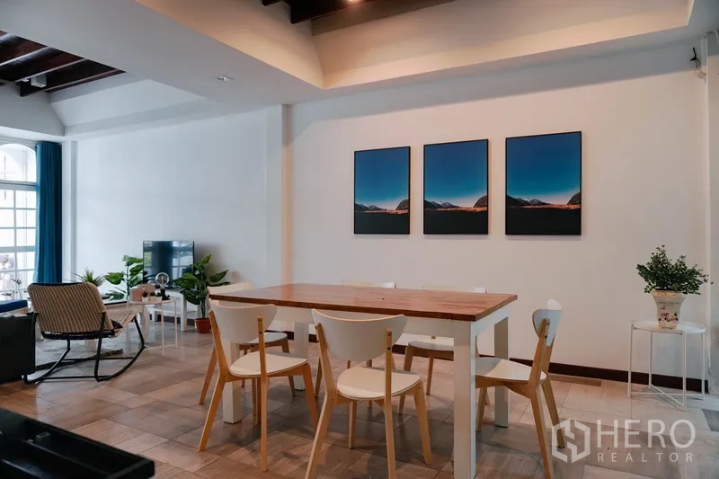 联排别墅 出租在Watthana, Bangkok - 开放式餐客厅，木质餐桌、电视区与室内绿植的曼谷联排别墅。