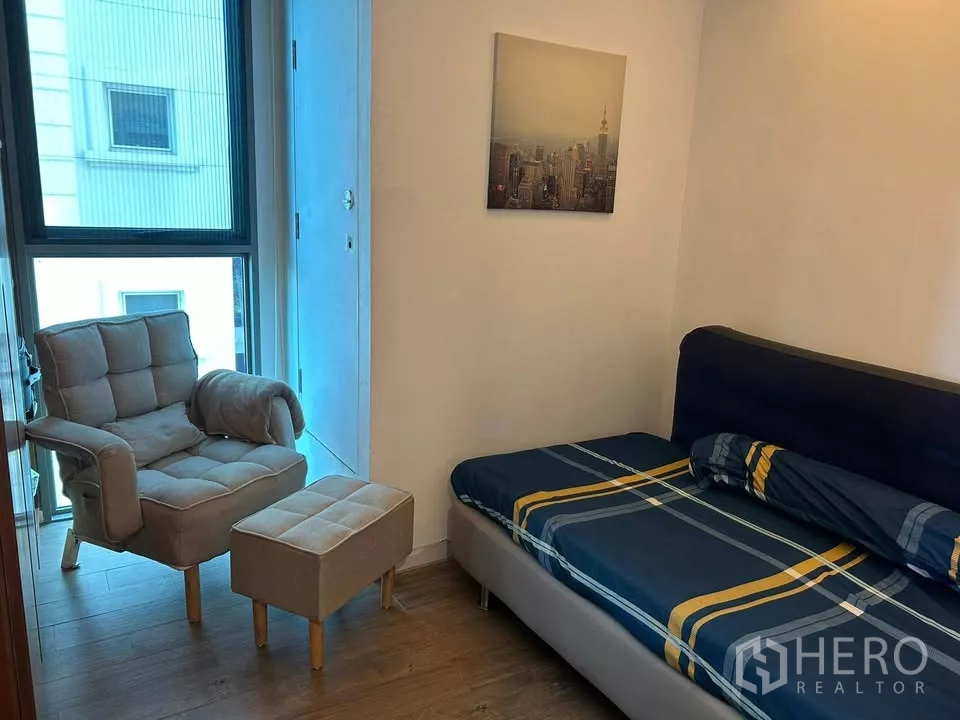公寓 出租在Watthana, Bangkok - 次卧配单人床与休闲扶手椅，旁有高窗