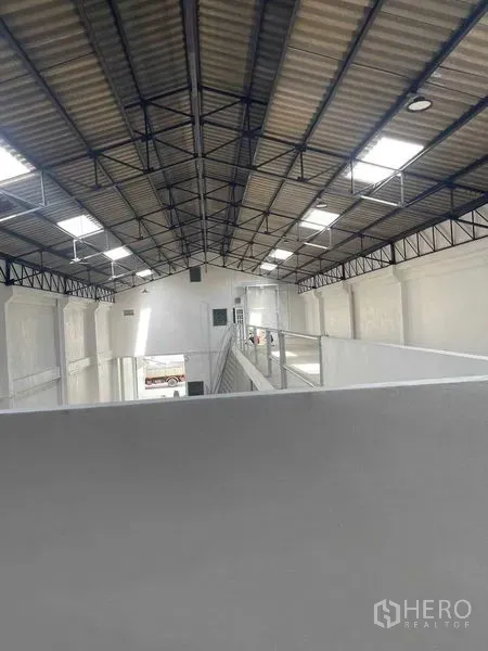 Warehouse for rent in Mueang Samut Sakhon, Samut Sakhon - View from the mezzanine showing steel-truss roof, skylight panels and safety railing inside the warehouse.