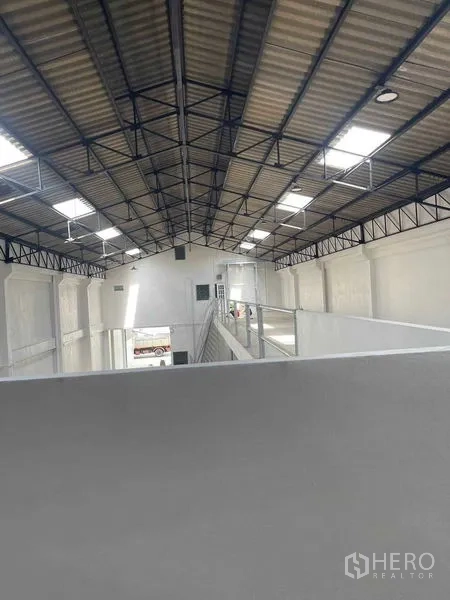 Warehouse for rent in Mueang Samut Sakhon, Samut Sakhon - View from the mezzanine showing steel-truss roof, skylight panels and safety railing inside the warehouse.