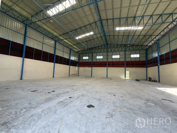 Warehouse for rent in Lam Luk Ka, Pathum Thani - Open storage space with blue steel columns, ventilation panels and natural light.