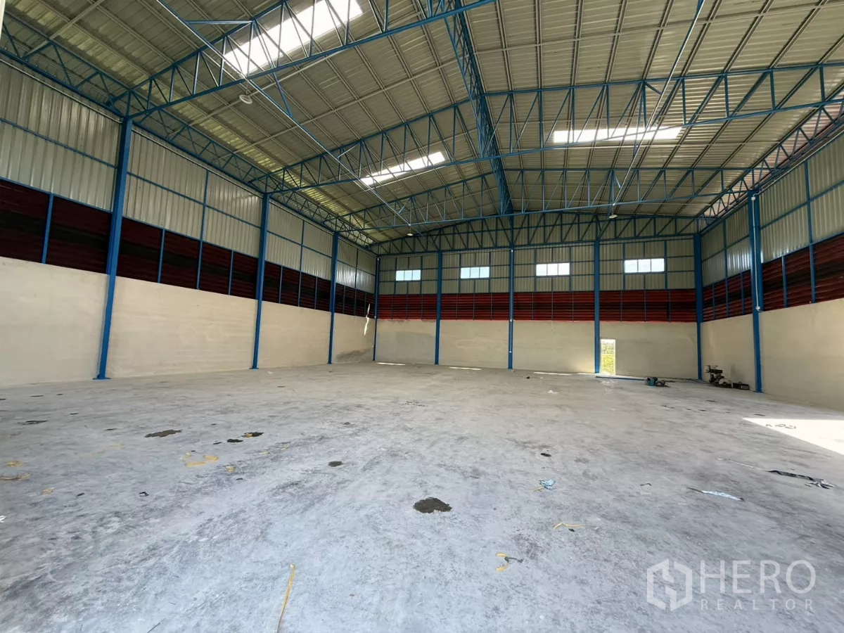 Warehouse for rent in Lam Luk Ka, Pathum Thani - Open storage space with blue steel columns, ventilation panels and natural light.