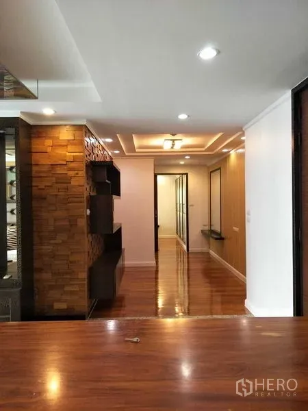 公寓 出租或出售在Watthana, Bangkok - 公寓走廊，吊顶筒灯与木质装饰墙，亮面实木地板，位于曼谷瓦他那区。