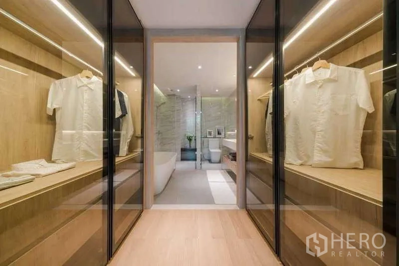 公寓 出租在Watthana, Bangkok - 走入式衣帽间，双侧玻璃柜，尽头连通大理石浴室。