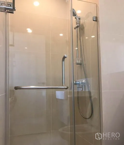 Condominium for rent in Huai Khwang, Bangkok - Modern bathroom featuring a glass‑enclosed shower with handheld sprayer.