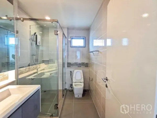 บ้าน ให้เช่าหรือขายในPrawet, Bangkok - ห้องน้ำสมัยใหม่พร้อมตู้กระจกอาบน้ำ อ่างล้างหน้า และผนังกระเบื้อง
