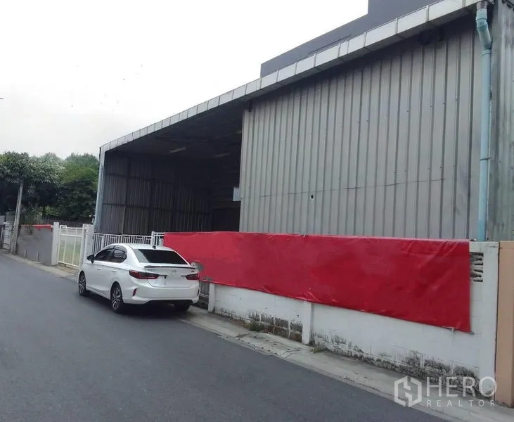 货栈 出租在Huai Khwang, Bangkok - 仓库外观，金属板立面与有顶装卸区，曼谷辉煌区小巷临街。