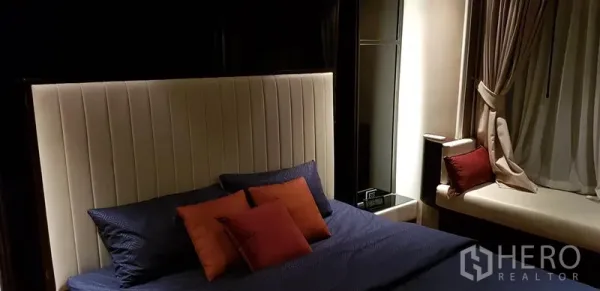 คอนโด ให้เช่าในRatchathewi, Bangkok - ห้องนอนบรรยากาศอบอุ่นยามค่ำ พร้อมหมอนตกแต่งและที่นั่งริมหน้าต่าง