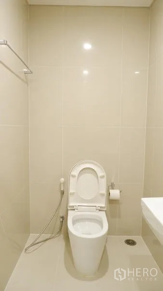 Condominium for rent in Watthana, Bangkok - Minimalist toilet room with bidet spray and tiled walls.