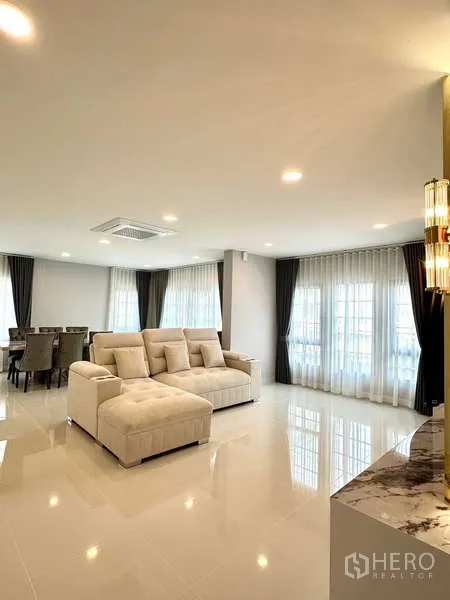 Detached House for rent in Bang Phli, Samut Prakan - Open-plan living and dining space with large sectional sofa and full-height windows.