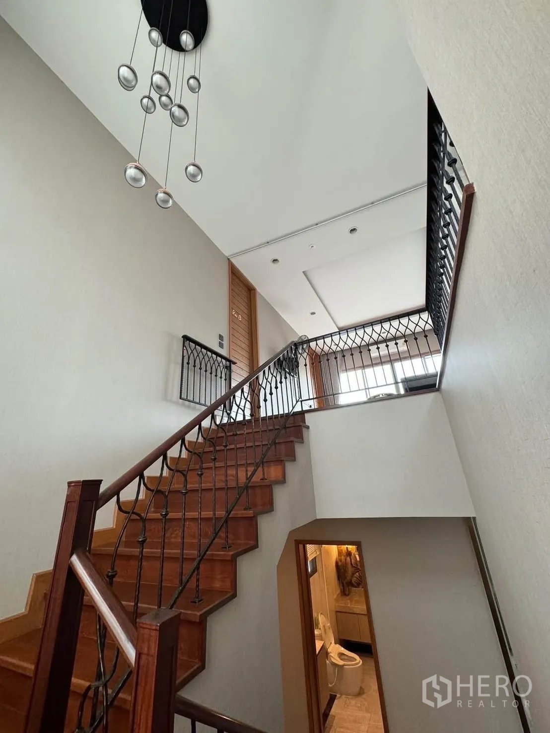 Detached House for rent in Prawet, Bangkok - Staircase with wood steps, wrought-iron balustrade and pendant lights.