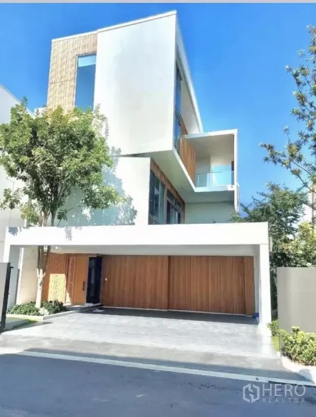บ้าน ให้เช่าในSaphan Sung, Bangkok - ด้านหน้าบ้านเดี่ยว 3 ชั้นสไตล์มินิมอล ประตูโรงจอดรถไม้ หน้าต่างบานใหญ่และระเบียงลอย