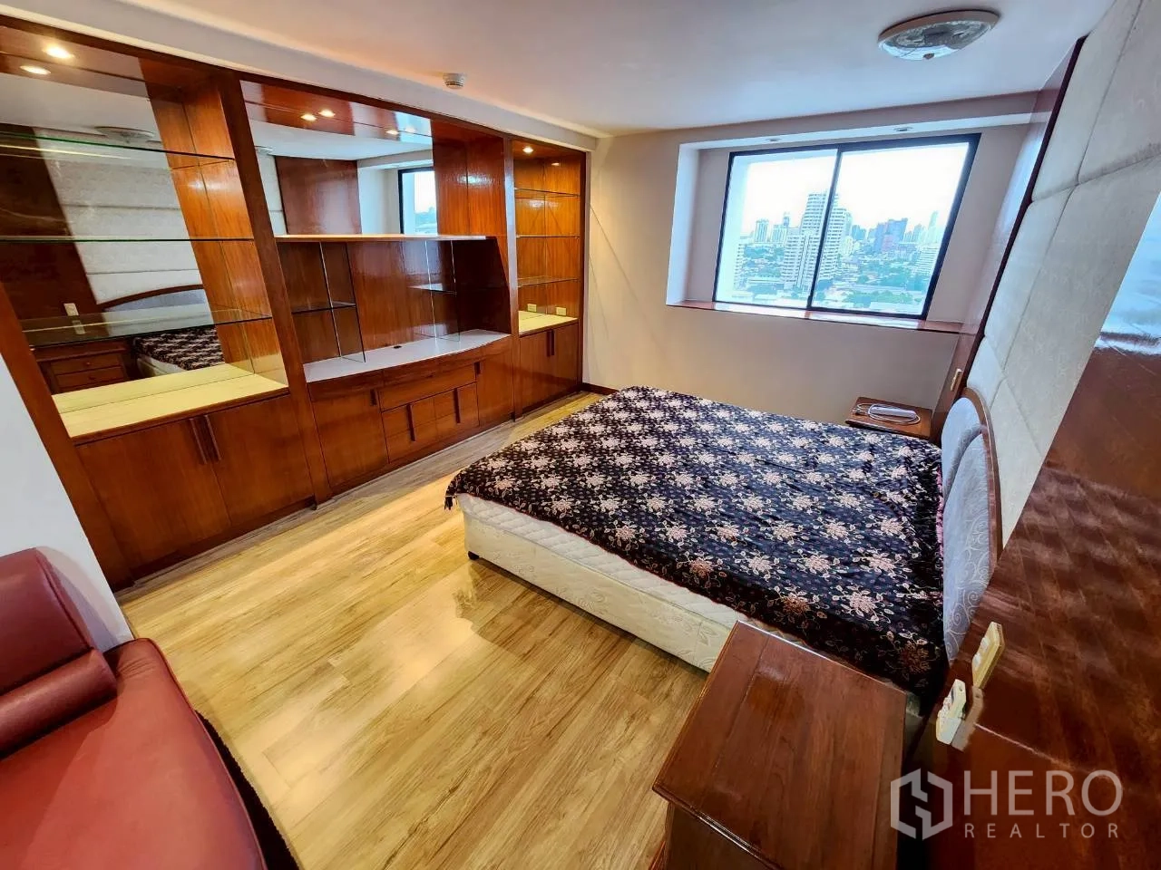 Condominium for rent in Khlong Toei, Bangkok - Bedroom with city-view window, built-in mirrored wardrobes and wood shelving.
