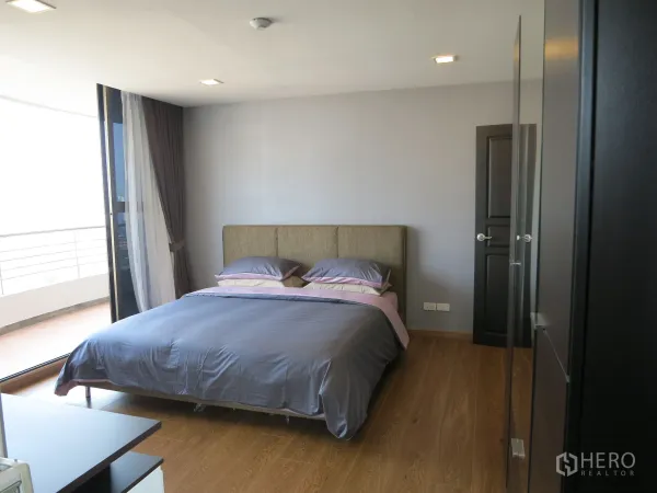 公寓 出租或出售在Watthana, Bangkok - 明亮卧室，木地板、双人床，落地推拉门通向阳台。