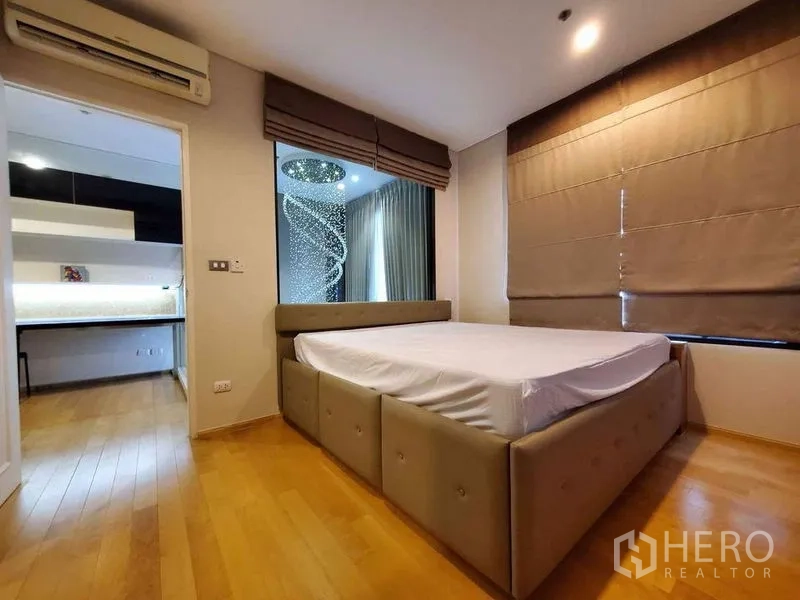 公寓 出租或出售在Ratchathewi, Bangkok - 卧室铺木地板，大床，窗外可见挑高吊灯区域。