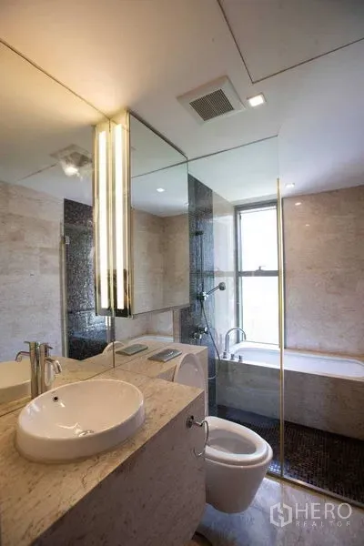 Condominium for rent in Yan Nawa, Bangkok - Contemporary bathroom with stone vanity, round basin, large mirror and windowed bathtub.