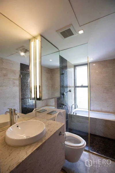 Condominium for rent in Yan Nawa, Bangkok - Contemporary bathroom with stone vanity, round basin, large mirror and windowed bathtub.
