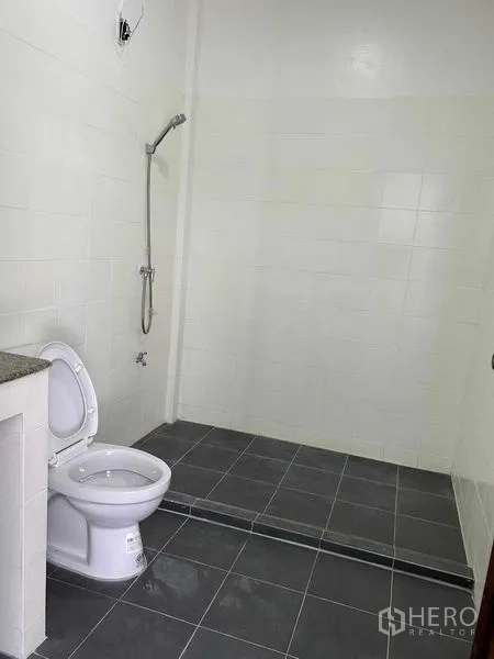 带办公室的家 出租或出售在Suan Luang, Bangkok - 极简浴室，步入式淋浴、坐便器与灰色地砖。