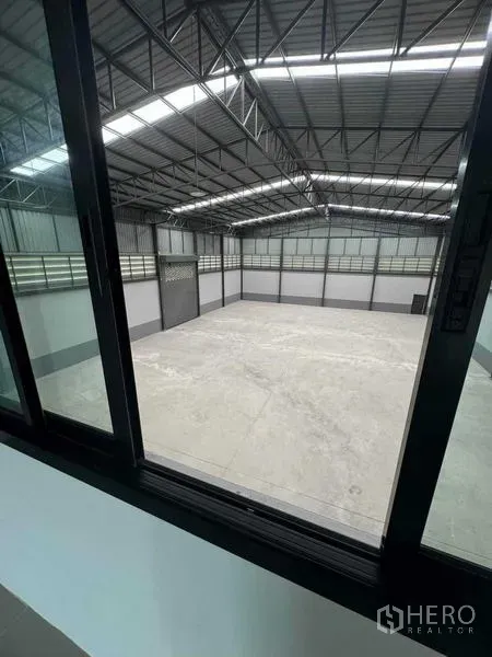 โรงงาน ขายในSamut Sakhon - มุมมองจากหน้าต่างออฟฟิศลงสู่โกดังเพดานสูงโครงหลังคาเหล็ก