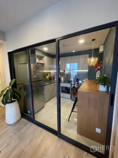 Condominium for sale - Kitchen enclosed by black-framed sliding glass doors adjacent to the living room.