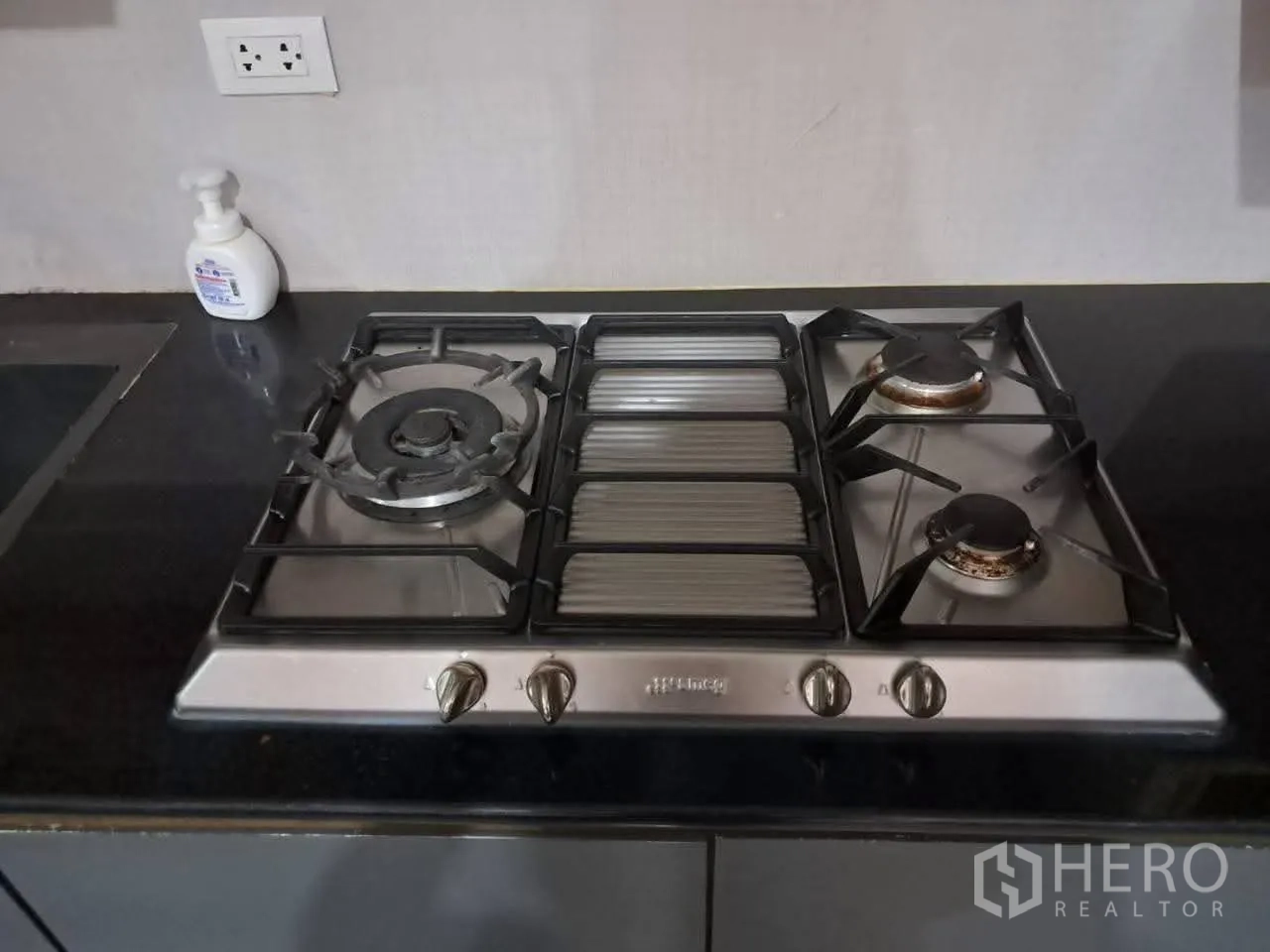 Townhouse for rent in Bang Kapi, Bangkok - Close-up of stainless steel gas hob with multiple burners on a black countertop.