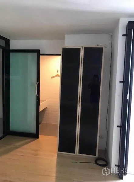 联排别墅 出租在Wang Thonglang, Bangkok - 卧室一角，衣柜与磨砂玻璃门的浴室入口。