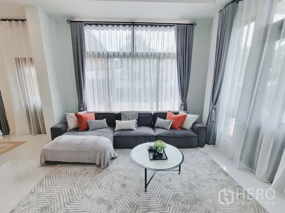 独栋房屋 for rent or sale in Bang Phli, Samut Prakan - 采光充足的起居角，L形沙发、图案地毯与落地窗。