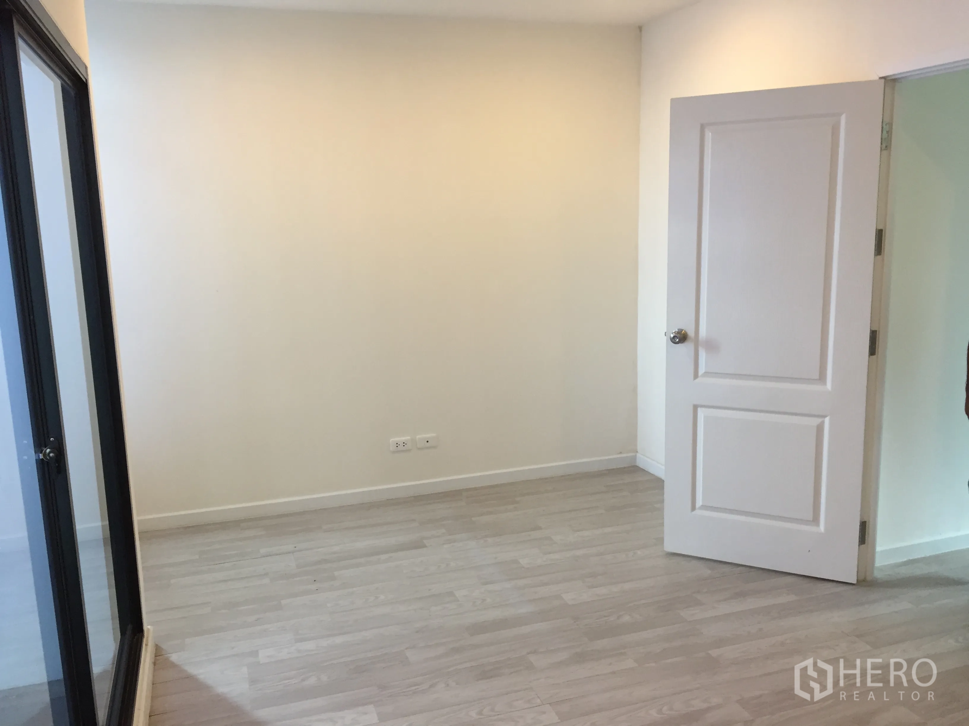 Townhouse for rent in Bang Kapi, Bangkok - Secondary bedroom with light wood floors, white door and mirrored sliding closet.