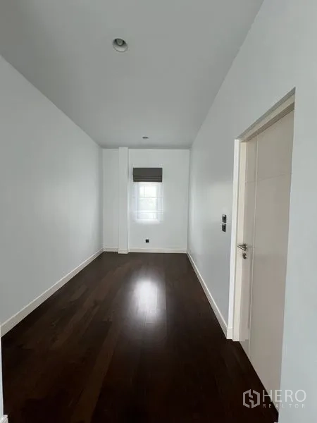 Detached House for rent in Bang Kapi, Bangkok - Narrow multipurpose room or study with white walls and dark wood flooring.