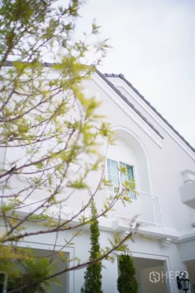 Detached House for rent in Bang Phli, Samut Prakan - Modern white two-storey detached house facade with arched balcony and greenery.