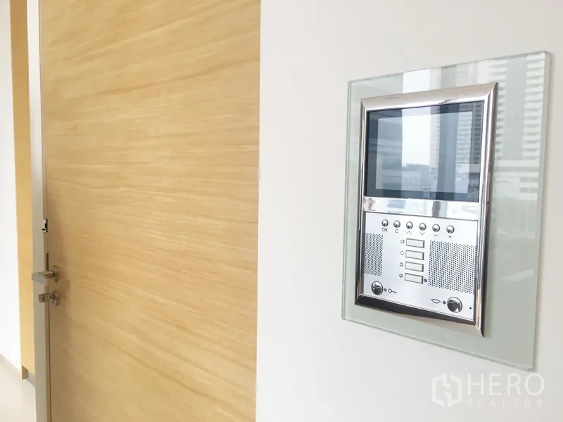 Condominium for rent in Bang Rak, Bangkok - Wall-mounted video intercom and secure entry panel next to a light wood door.