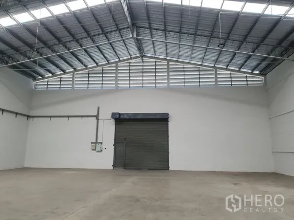 货栈 出租在Khlong Luang, Pathum Thani - 仓库内配有大卷闸门、通风百叶与白色墙面。