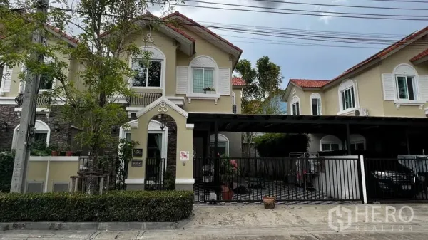 独立式住宅 出租或出售在Pathum Thani - 两层独栋住宅外观，带大门车道与红瓦屋顶，位于巴吞他尼市。