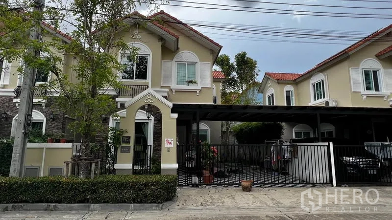 独立式住宅 出租或出售在Pathum Thani - 两层独栋住宅外观，带大门车道与红瓦屋顶，位于巴吞他尼市。