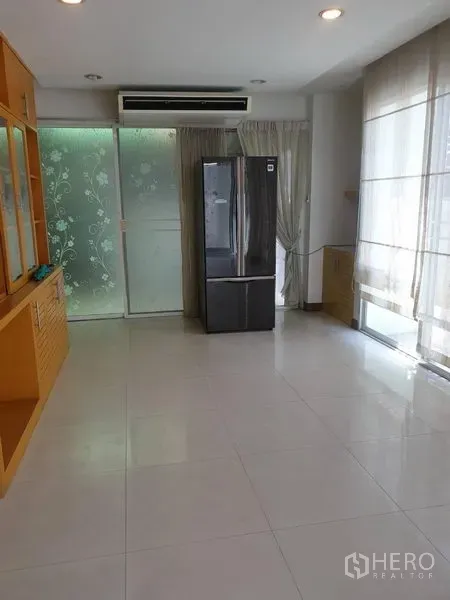Townhouse for rent or sale in Yan Nawa, Bangkok - Bright tiled living and dining space with floor-to-ceiling curtains, frosted glass sliding door and refrigerator.