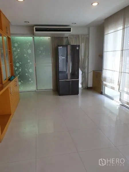 Townhouse for rent or sale in Yan Nawa, Bangkok - Bright tiled living and dining space with floor-to-ceiling curtains, frosted glass sliding door and refrigerator.
