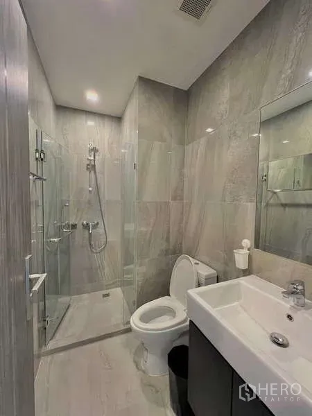 คอนโด ขายในWatthana, Bangkok - ห้องน้ำสมัยใหม่พร้อมตู้กระจกอาบน้ำ กระเบื้องสีเทา อ่างล้างหน้า และโถสุขภัณฑ์