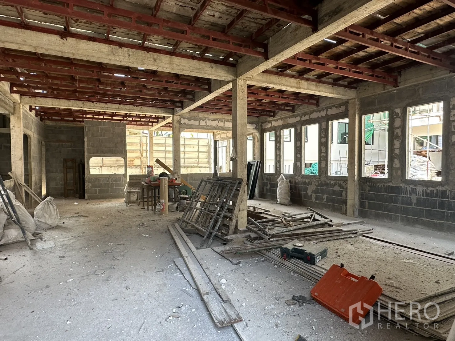 零售空间 for rent in Bang Na, Bangkok - 一层开放式空间，混凝土柱与红色钢梁，多扇窗洞。