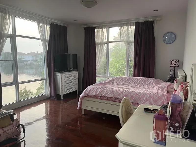 Detached House for rent or sale in Lat Krabang, Bangkok - Corner master bedroom with panoramic windows and wood flooring overlooking the lake.
