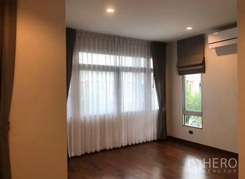 独立式住宅 出租在Lat Krabang, Bangkok - 转角卧室，木地板，大窗与窗帘。