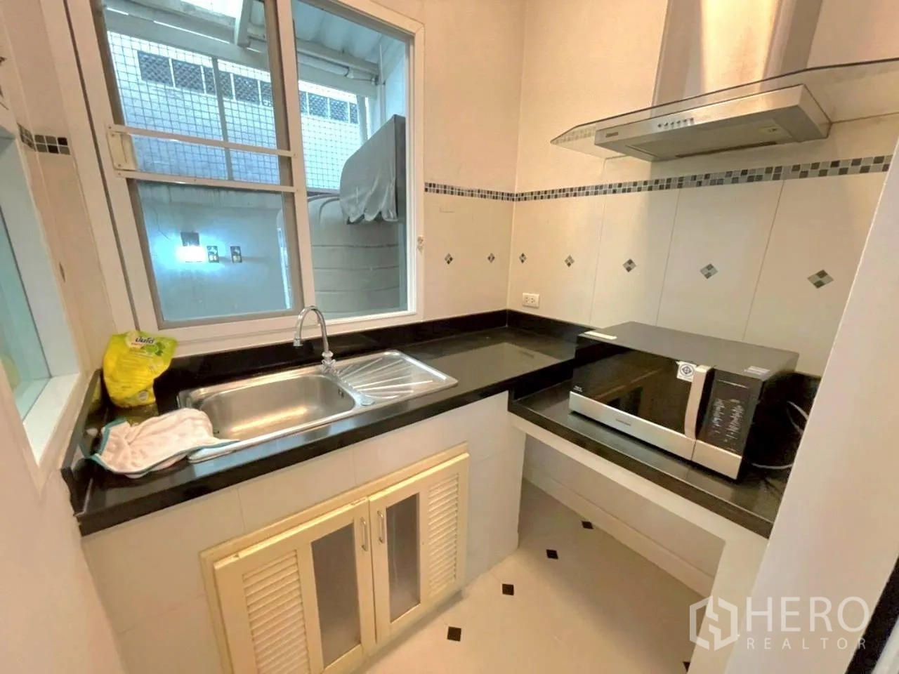 Townhouse for rent in Bang Kho Laem, Bangkok - Compact kitchen with black countertops, stainless sink, range hood and microwave.