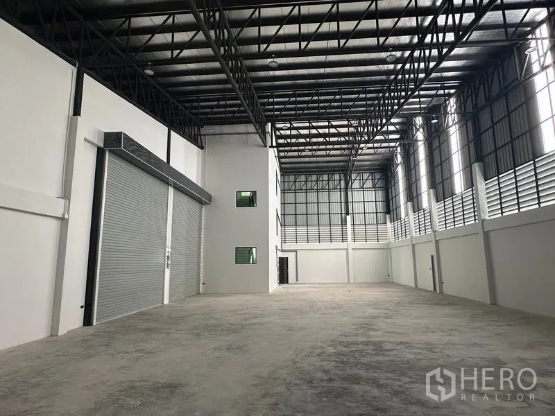 Warehouse for sale in Lam Luk Ka, Pathum Thani - Expansive warehouse bay with twin roller shutters and insulated metal roof.