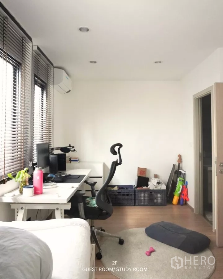 联排别墅 出租在Suan Luang, Bangkok - 采光充足的书房/客卧，长书桌、人机工学椅与百叶窗。
