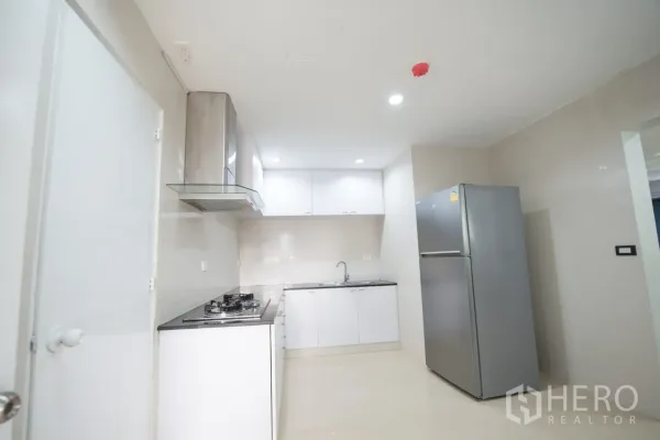 公寓 出租或出售在Khlong Toei, Bangkok - 现代白色厨房，燃气灶、抽油烟机、充足橱柜与不锈钢冰箱。