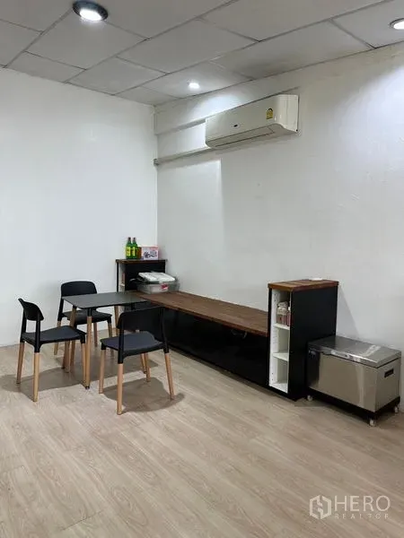 Shophouse for rent in Khlong Toei, Bangkok - Compact meeting corner with table, four chairs, a long sideboard and wall-mounted air conditioner.