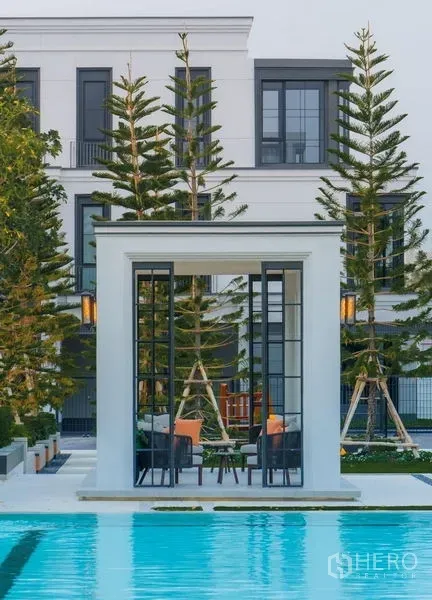 Detached House for sale in Saphan Sung, Bangkok - Poolside pavilion with white frame structure, seating area and tall evergreens in a luxury estate.