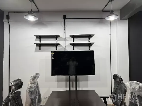 带办公室的家 出租在Pom Prap Sattru Phai, Bangkok - 会议区墙面设置置物架与挂装电视，外露管线与吊灯。